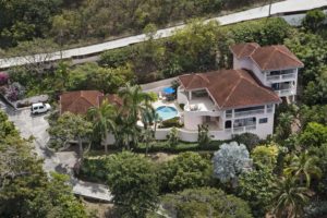 An aerial shot of a luxurious Virgin Gorda Villa Rental surrounded by lush greenery, featuring a private pool and a well-maintained garden.