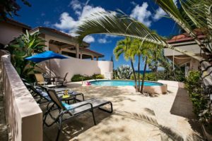 An aerial shot of a luxurious Virgin Gorda Villa Rental surrounded by lush greenery, featuring a private pool and a well-maintained garden.