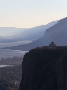 A stunning cliffside scene featuring a historic observatory perched atop a steep hill, overlooking a serene lake.