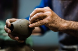 Close-up of hands meticulously shaping a ceramic pot, showcasing traditional craftsmanship at Adagio Villa Resort.