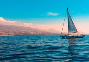 Sailors enjoying a scenic voyage on a white sailing yacht with billowing sails at Adagio Villa Resort.