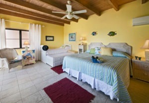 Bright and cheerful guest room with yellow walls, a comfortable bed, and a cozy seating area for families at Adagio Villa Resort.