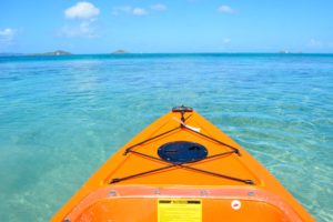Orange kayak floating on turquoise waters with a clear blue sky and distant islands in the background at Adagio Villa Resort.