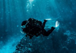 Scuba diver exploring the underwater world with sunlight streaming through the water at Adagio Villa Resort.