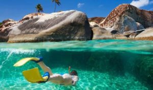 Snorkeler exploring turquoise waters with large rock formations and vibrant marine life at Adagio Villa Resort.
