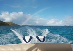 Speedboat cruising through turquoise waters with a stunning rainbow in the sky at Adagio Villa Resort.