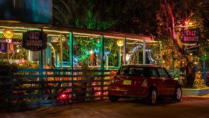 Colorful nighttime restaurant with neon signs, festive lights, and a classic red car parked outside at Adagio Villa Resort.