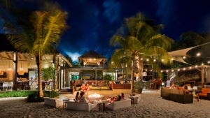 Beachside lounge with string lights, palm trees, and cozy seating under the stars at Adagio Villa Resort.