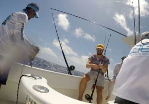 Fishermen reeling in a catch while enjoying a deep-sea fishing trip on a yacht at Adagio Villa Resort.