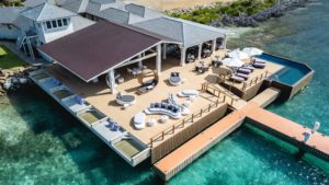 Luxurious waterfront lounge with modern design, comfortable seating, and a dock overlooking clear turquoise waters at Adagio Villa Resort.