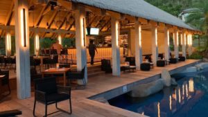 Modern outdoor bar and lounge area with warm lighting, overlooking a tranquil pool at Adagio Villa Resort.