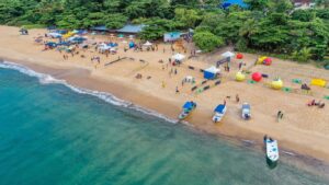 Aerial view of tropical beach with luxury villas in Virgin Gorda, colorful umbrellas, and private boats at Adagio Villa Resort.